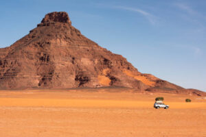 A 4x4 car in the typical landscape of the remote Ennedi Mountains (massif) in the Sahara desert, North-East Chad. The Ennedi massif was declared as an UNESCO World Heritage site in 2016.